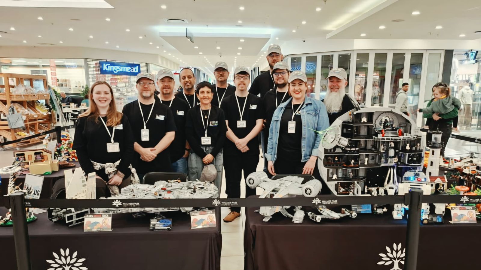 The ECLug team in matching caps and lanyards standing behind their display tables at Walmer Park, with a LEGO Death Star and Millennium Falcons in front