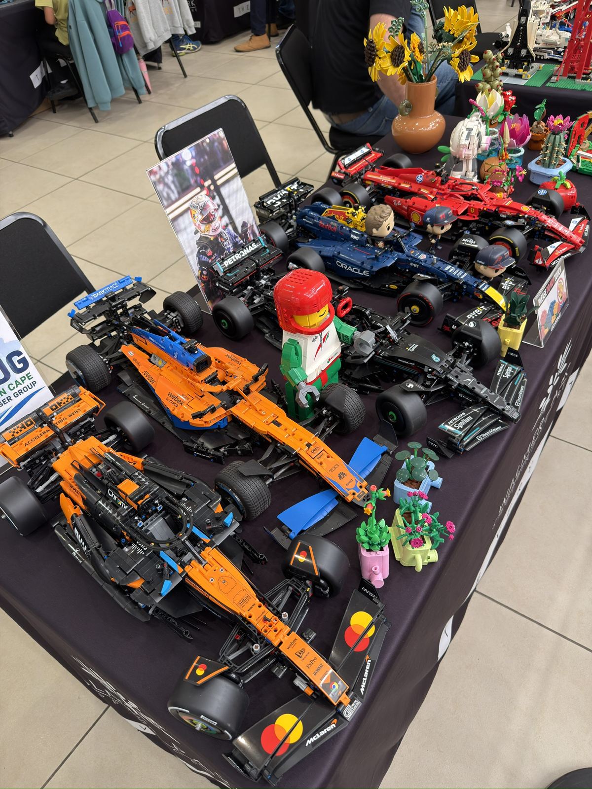 A row of LEGO Technic Formula 1 cars on a black tablecloth