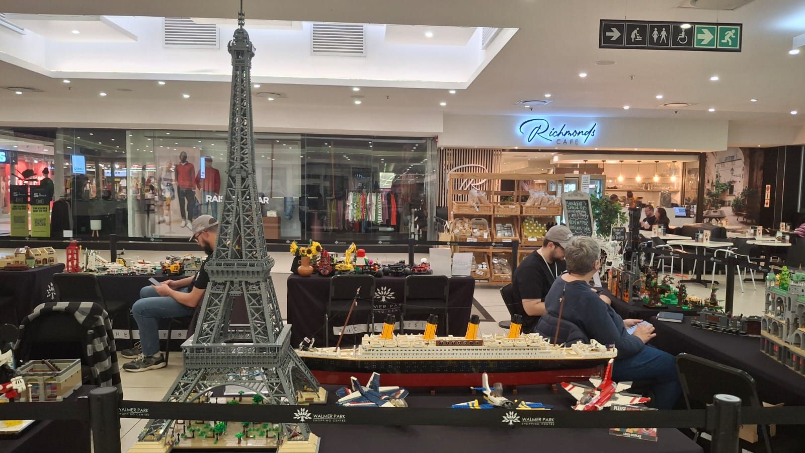 Wide view of the ECLug display tables in the mall, with a tall LEGO Eiffel Tower in the centre