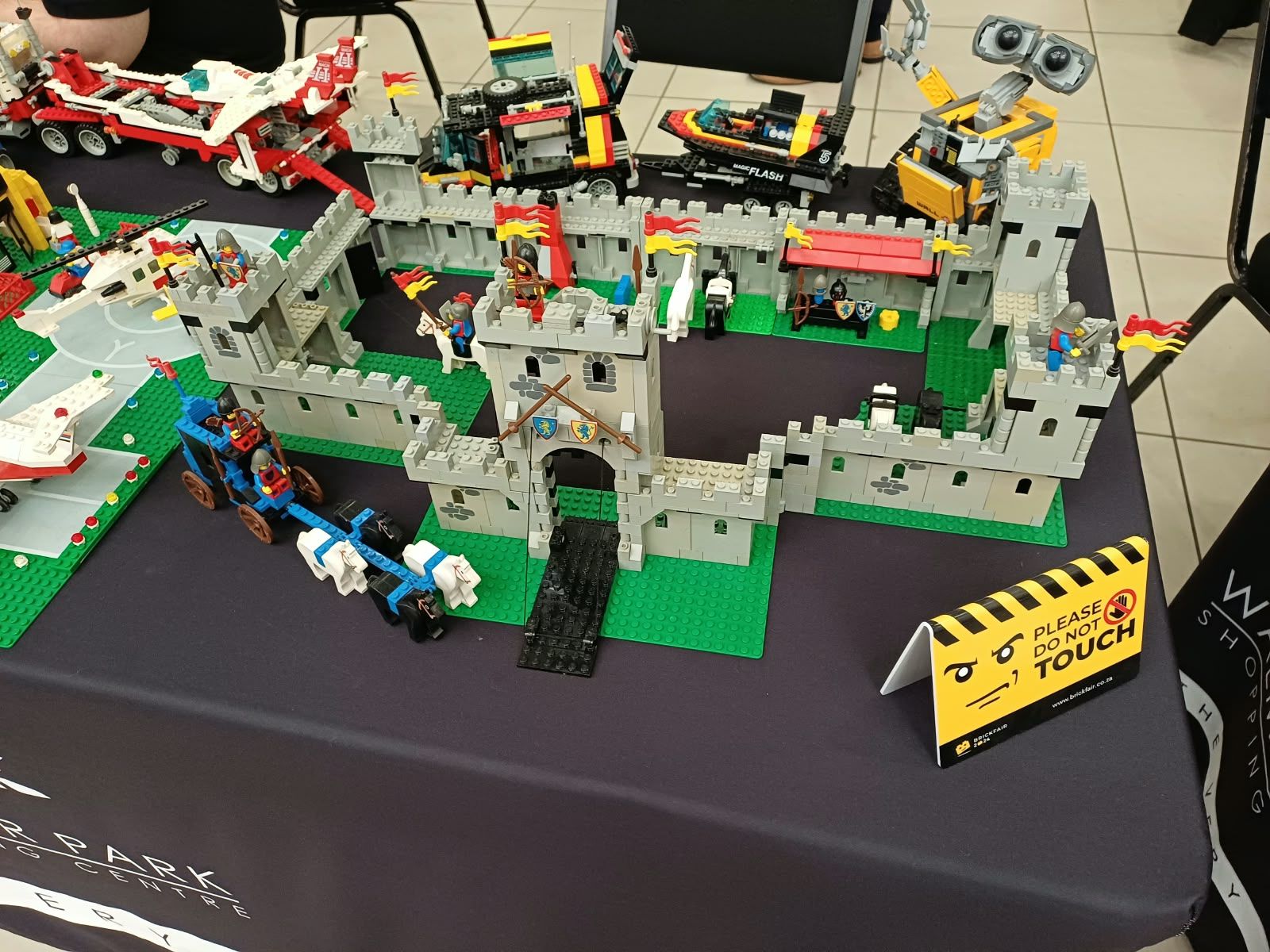 A classic grey LEGO castle on a green baseplate, surrounded by vehicles
