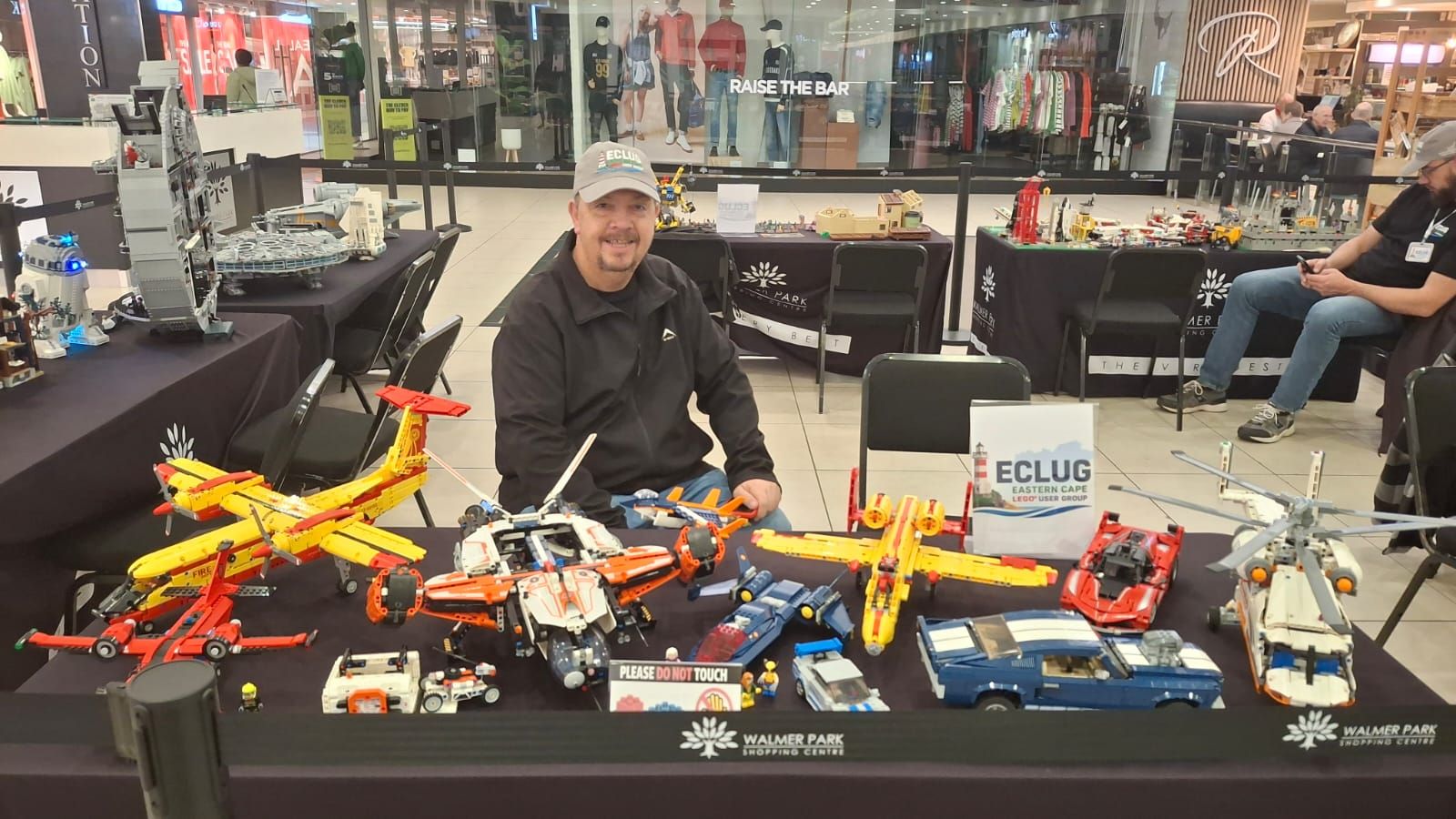 A smiling ECLug member behind a table of LEGO aircraft and cars